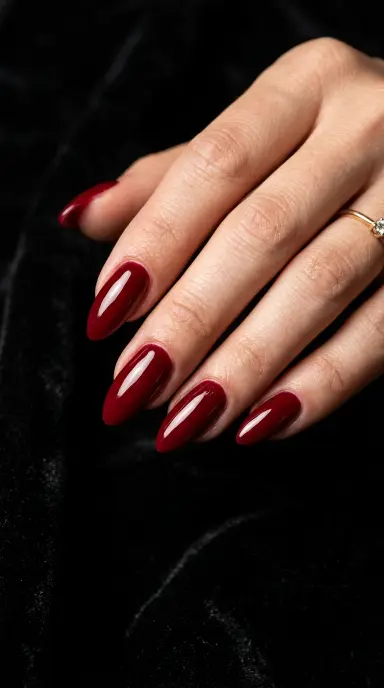 Bold macro close-up of almond-shaped nails in a deep cherry red with a high-gloss finish