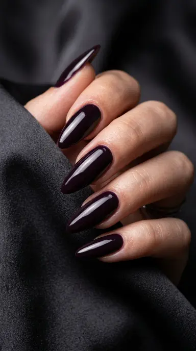 Dramatic macro close-up of long almond nails in a deep plum noir