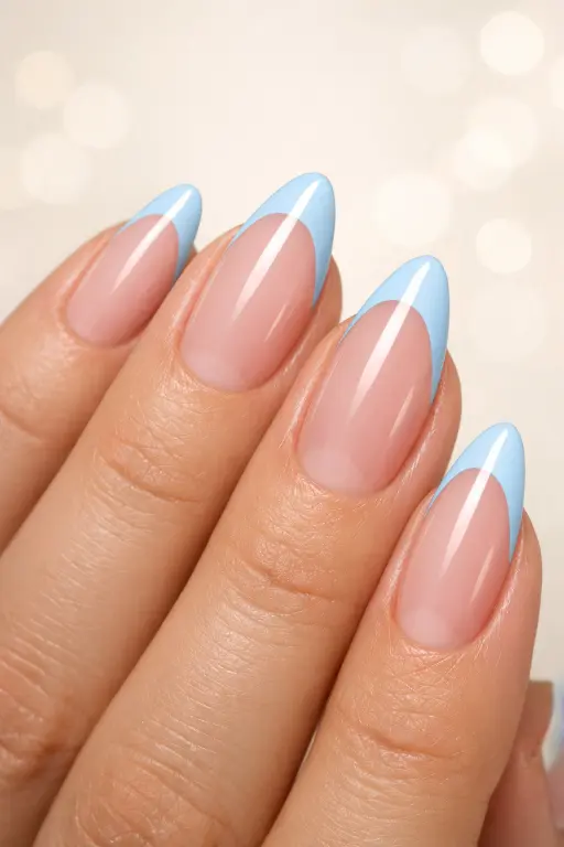 Macro close up of a woman's hand displaying modern French tip nails with baby blue tips on a clear natural base