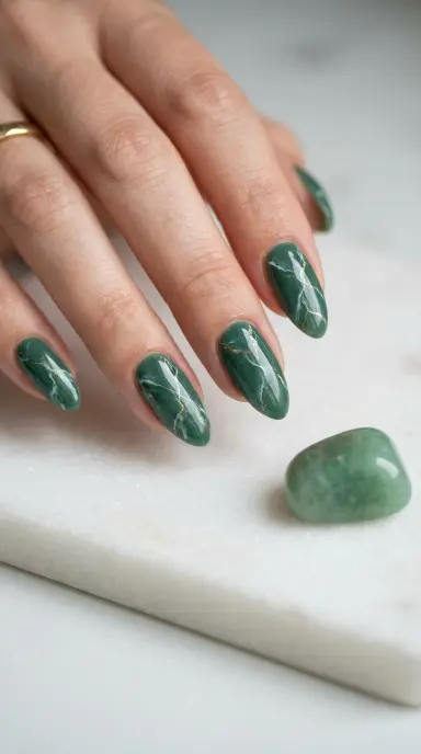 Macro editorial photograph of almond-shaped nails in a deep jade green