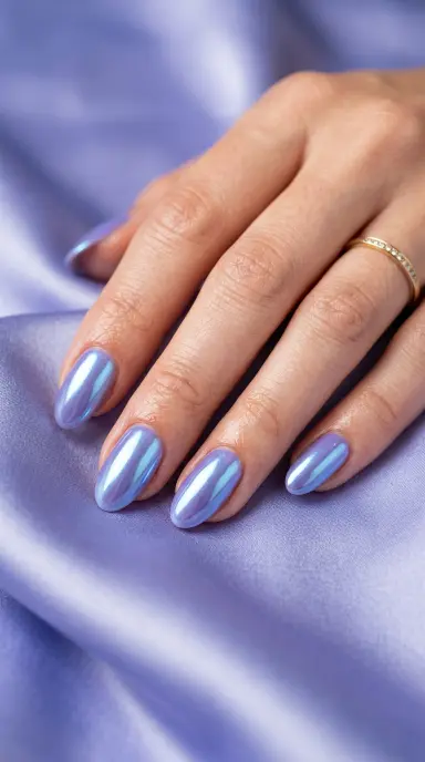 Macro editorial photograph of oval nails painted in a soft periwinkle purple with a metallic chrome finish